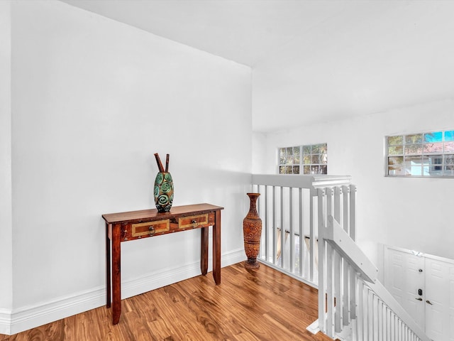 hall featuring baseboards, an upstairs landing, and wood finished floors