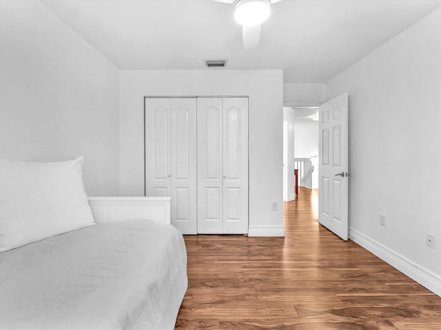 bedroom with a closet, visible vents, ceiling fan, wood finished floors, and baseboards
