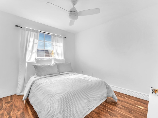 bedroom with a ceiling fan, baseboards, and wood finished floors