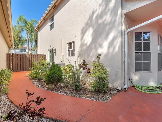 view of side of property with a patio area, fence, and stucco siding