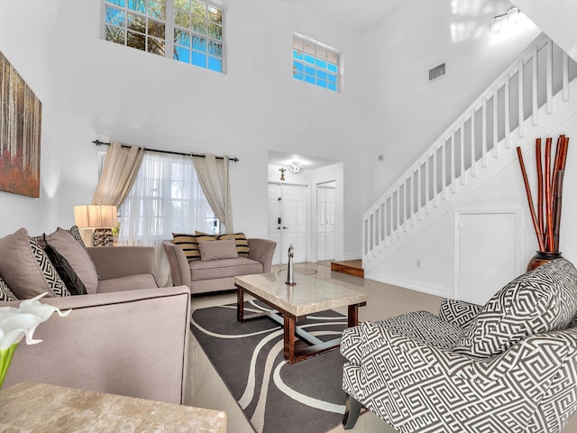 living area with visible vents, a towering ceiling, baseboards, and stairs