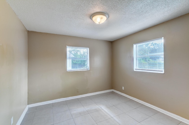 tiled spare room with baseboards and a textured ceiling