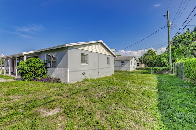 view of side of property featuring fence, a lawn, and stucco siding