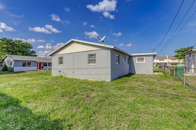 back of property with stucco siding, fence, and a yard