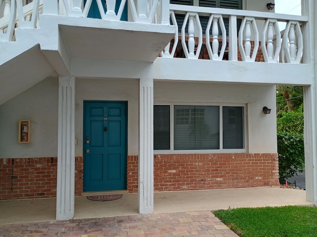 property entrance with stucco siding and brick siding