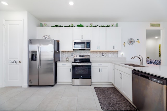 kitchen featuring appliances with stainless steel finishes, white cabinets, light countertops, and a sink