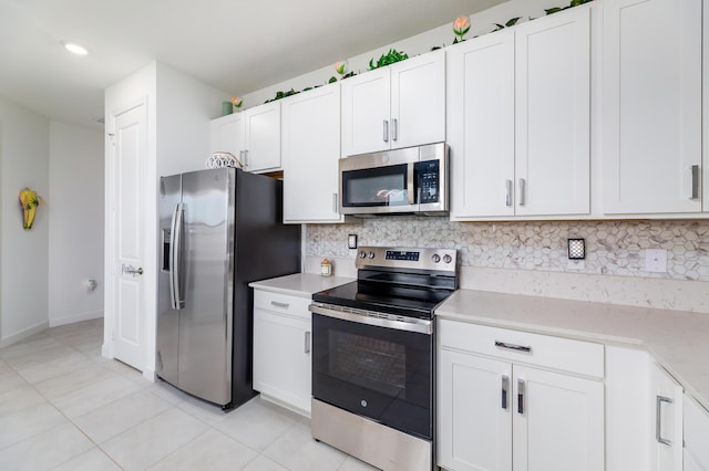 kitchen with light tile patterned floors, white cabinetry, baseboards, appliances with stainless steel finishes, and backsplash