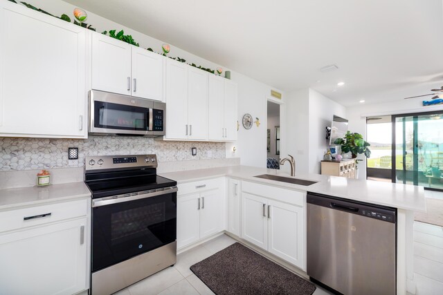 kitchen with stainless steel appliances, a peninsula, a sink, and light countertops