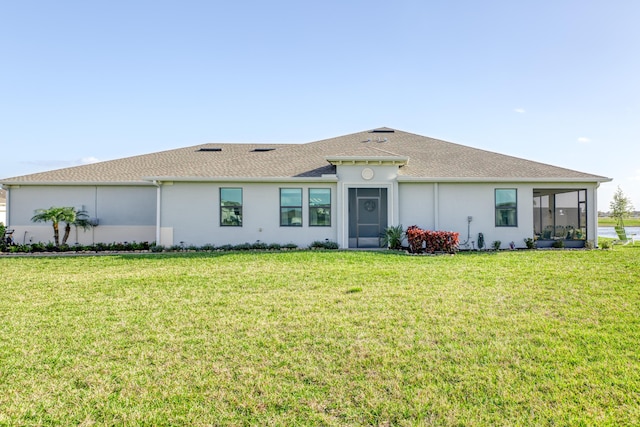 view of front of home featuring roof with shingles, a front yard, a sunroom, and stucco siding