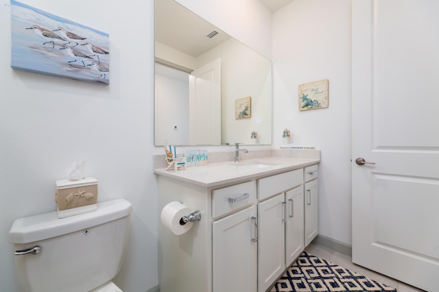 bathroom with toilet, vanity, and visible vents