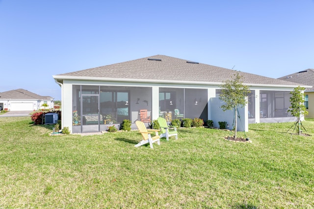 rear view of house with a sunroom, a lawn, and central AC unit