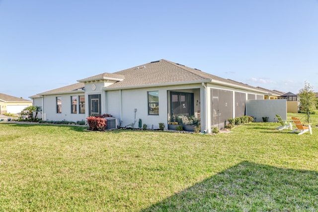 back of property featuring central air condition unit, stucco siding, a sunroom, and a yard