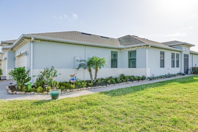 view of property exterior with an attached garage, stucco siding, roof with shingles, and a yard