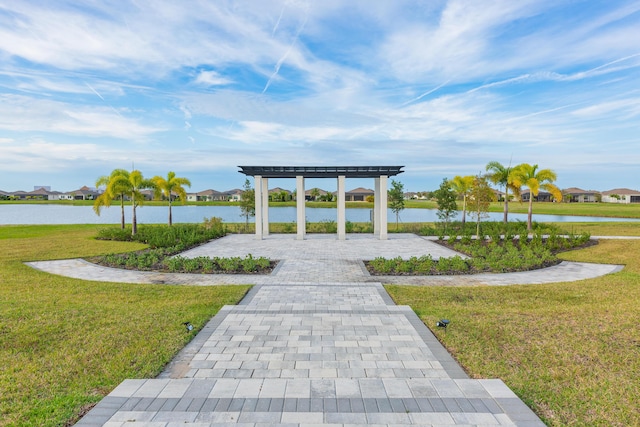 view of home's community with a yard, a water view, and a pergola