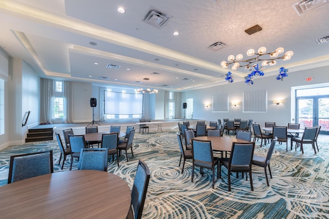 dining room with a chandelier, a tray ceiling, plenty of natural light, and visible vents