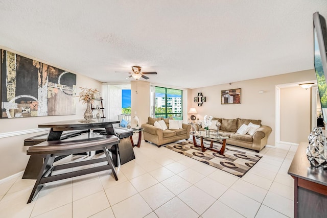 living area featuring tile patterned flooring, ceiling fan, a textured ceiling, and baseboards