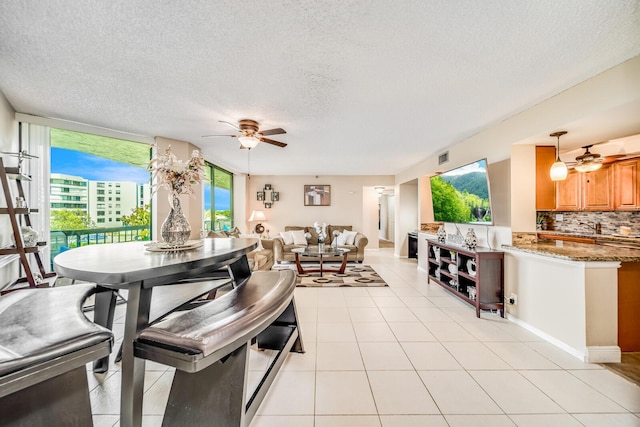 dining space featuring ceiling fan, a textured ceiling, light tile patterned flooring, and visible vents