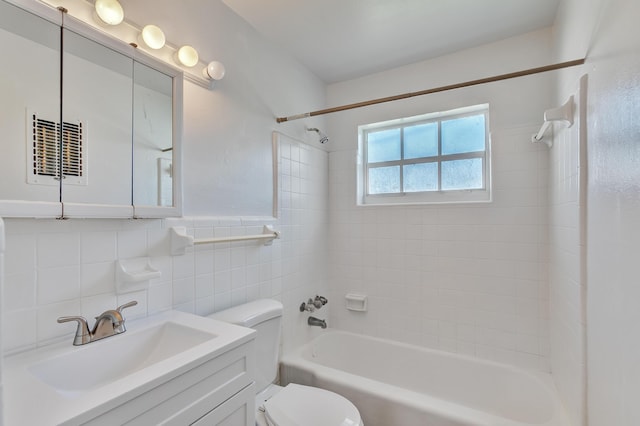 bathroom featuring a wainscoted wall, tile walls, toilet, washtub / shower combination, and vanity