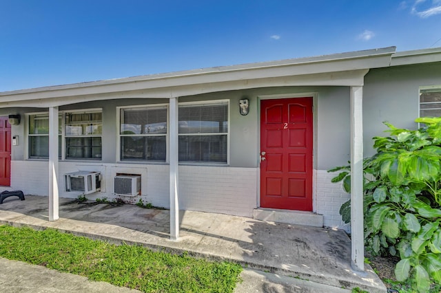 view of exterior entry with covered porch and brick siding