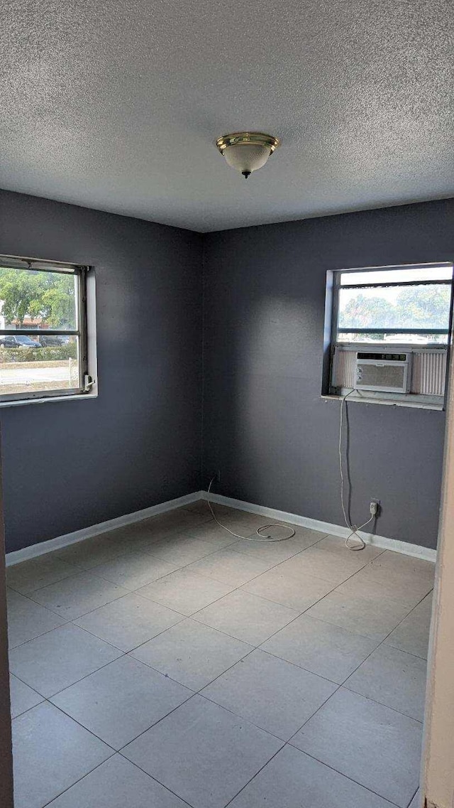 unfurnished room with cooling unit, a textured ceiling, and baseboards