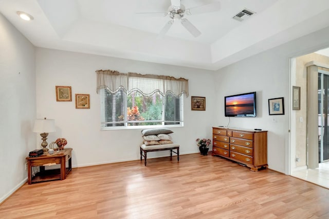 sitting room with visible vents, a raised ceiling, baseboards, ceiling fan, and light wood-style flooring