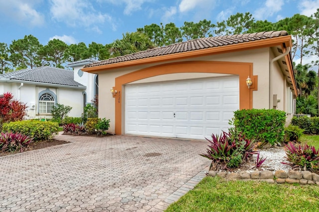 view of front of home featuring a garage, a tiled roof, decorative driveway, and stucco siding