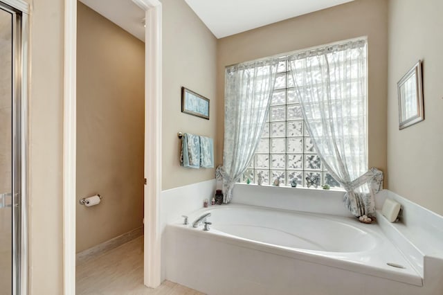 full bathroom featuring a garden tub and a wealth of natural light