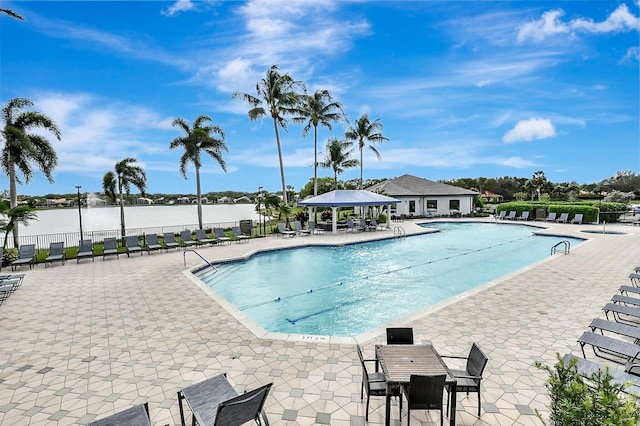 community pool with a patio area, fence, and a gazebo