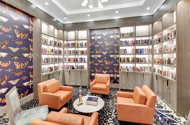 sitting room featuring recessed lighting, a raised ceiling, and bookshelves