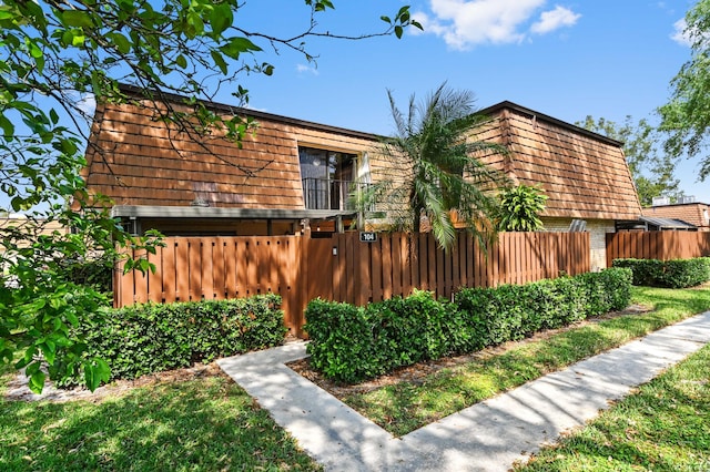 exterior space with mansard roof, brick siding, and fence