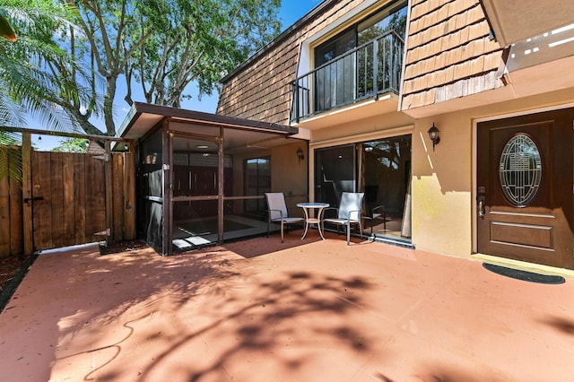 view of patio featuring fence, a balcony, and a sunroom