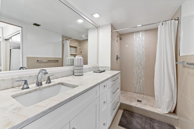 bathroom featuring vanity, visible vents, and a tile shower