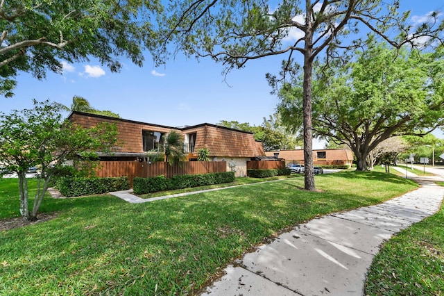 view of side of property with mansard roof and a lawn