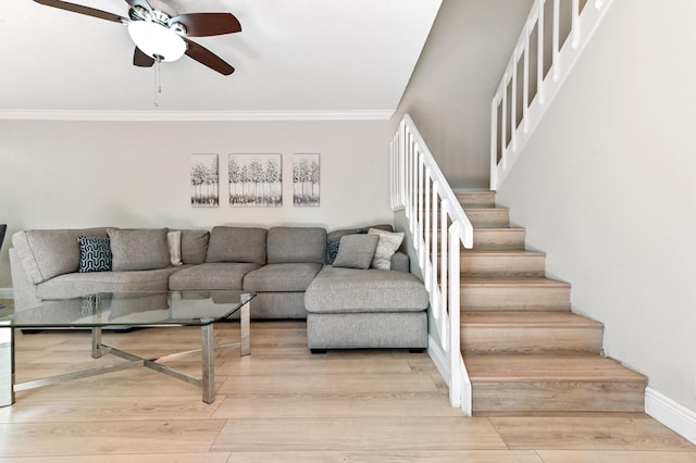 living room featuring a ceiling fan, baseboards, ornamental molding, stairs, and light wood-style floors