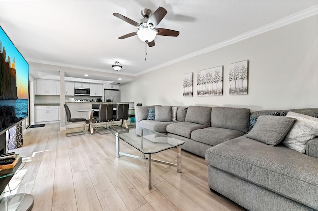 living area featuring light wood-style flooring, a ceiling fan, and ornamental molding