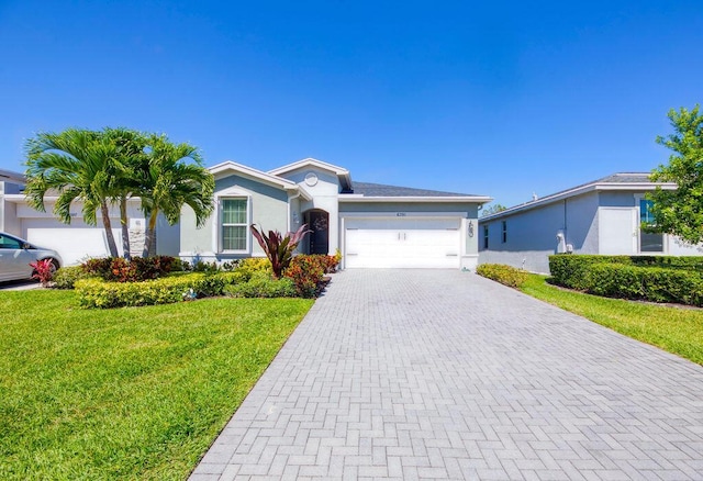 single story home featuring a front lawn, decorative driveway, an attached garage, and stucco siding