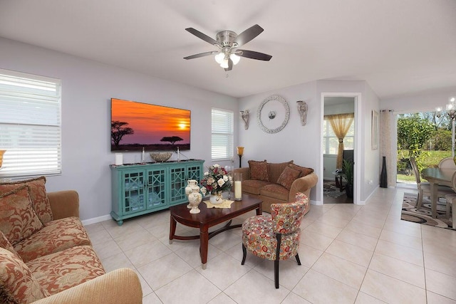 living area featuring baseboards, ceiling fan with notable chandelier, and light tile patterned flooring