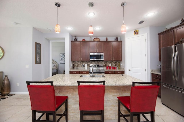 kitchen featuring a breakfast bar area, tasteful backsplash, visible vents, appliances with stainless steel finishes, and a sink