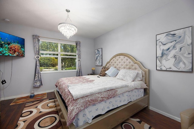 bedroom featuring an inviting chandelier, baseboards, and wood finished floors