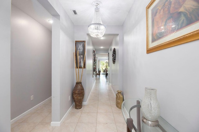 hall with an inviting chandelier, baseboards, visible vents, and light tile patterned flooring