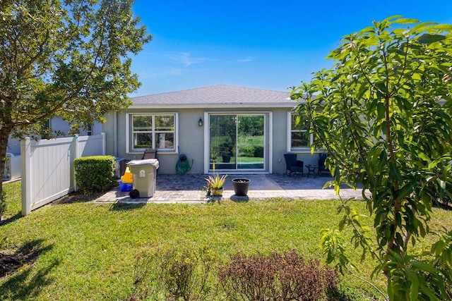 back of house with a lawn, a gate, fence, a patio area, and stucco siding