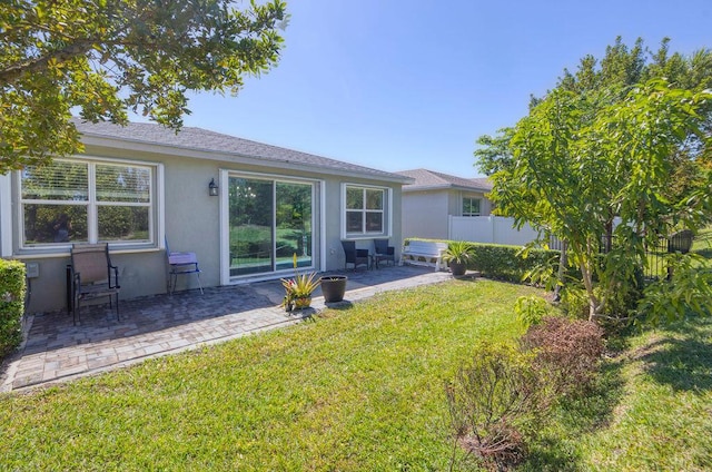 back of property with a yard, a patio, fence, and stucco siding