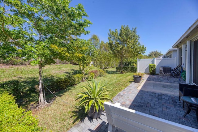 view of yard featuring a patio area, fence, and central AC