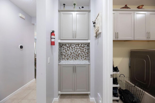 interior space featuring light tile patterned floors, washer / clothes dryer, cabinet space, and baseboards