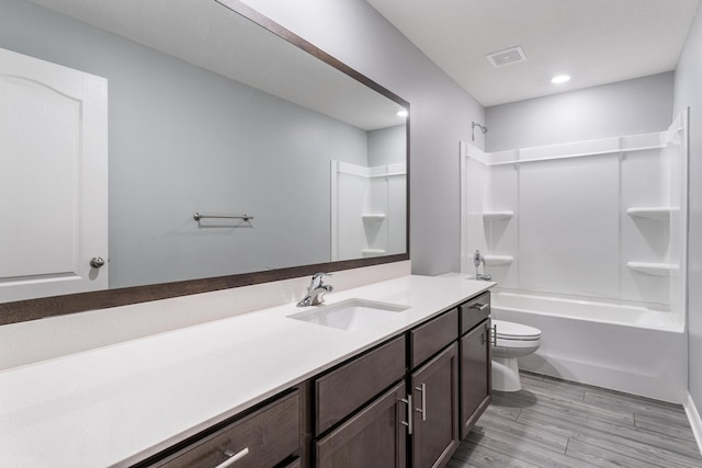 full bathroom with visible vents, toilet, wood finished floors, bathing tub / shower combination, and vanity