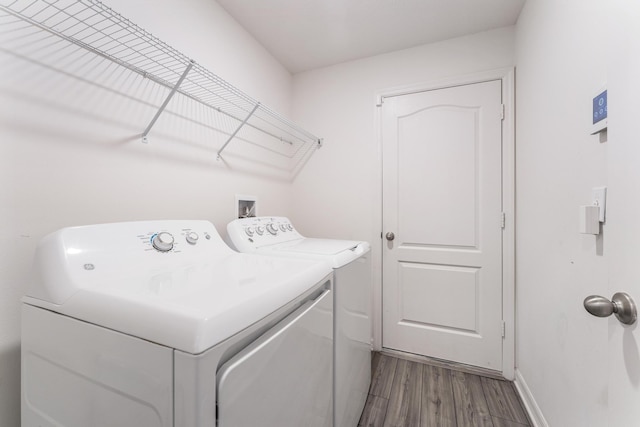 clothes washing area with laundry area, independent washer and dryer, dark wood-type flooring, and baseboards