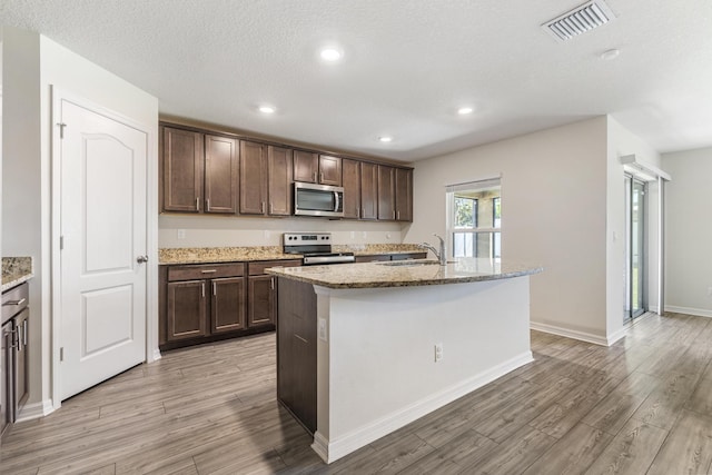 kitchen with visible vents, dark brown cabinets, appliances with stainless steel finishes, and light wood-type flooring