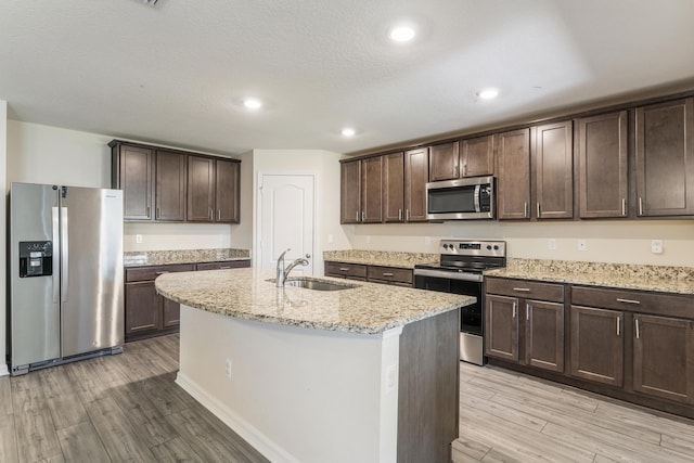 kitchen featuring a sink, light wood-type flooring, appliances with stainless steel finishes, and dark brown cabinets