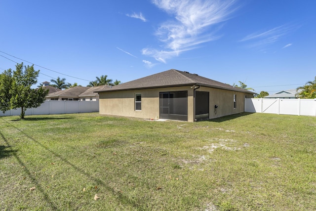 rear view of house featuring a yard, a fenced backyard, and stucco siding