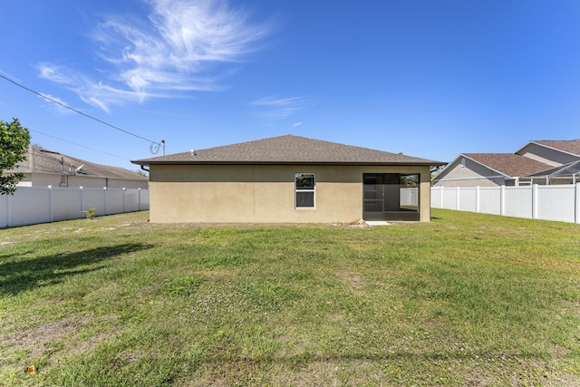 back of property featuring a sunroom, a lawn, a fenced backyard, and stucco siding